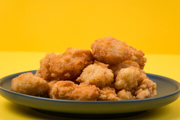 A plate of fried chicken with yellow background