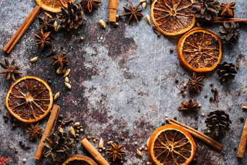 Cinnamon, cloves, pepper, dried oranges and anise on a grey background. Frame. Place for your text