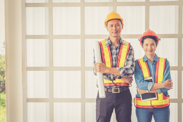 Worker standing and look building under construction with plan paper at construction site.