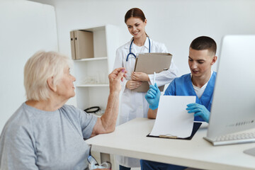 Fototapeta premium nurse and doctor examining an elderly woman hospital diagnosis