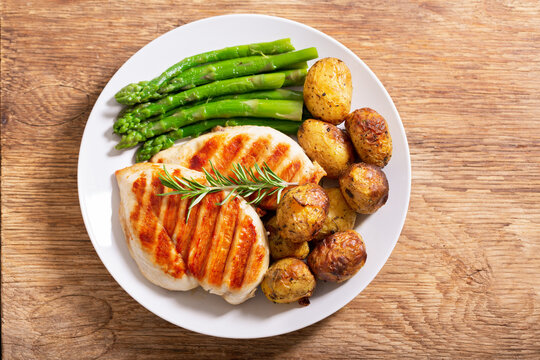 plate of grilled chicken, asparagus and baked potatoes, top view