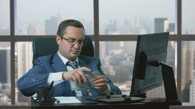 Man with suit sit at office, counting money an put it in wallet, daily balance, results of hardwork
