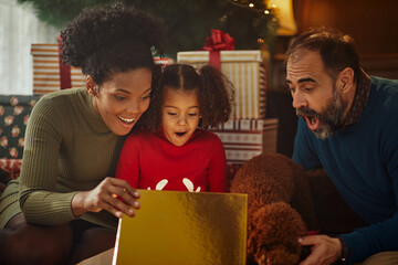 Biracial family unwrapping Christmas gifts and celebrating holidays at home - Powered by Adobe