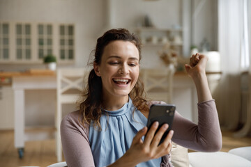 Happy surprised smartphone user receiving amazing good news on smartphone, reading message, making...