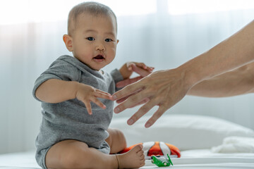 Infant asian. An Asian baby trusts his father's hand to stand up. father and son spending time together