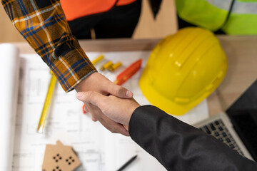 Real estate agent shakes hands with construction team leader. Business agrees to sign a home...
