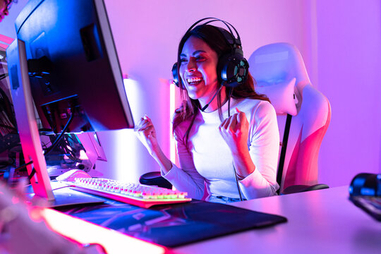 young  playing game online at home. Gamer  controlling joystick for video game. Teenage girls leisure game in neon light room at home.