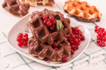 Waffles with chocolate topping, red currant and hazelnuts.