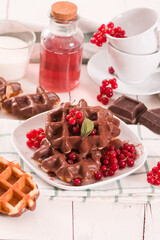 Waffles with chocolate topping, red currant and hazelnuts.