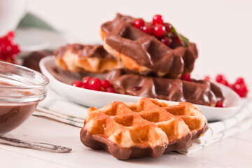 Waffles with chocolate topping, red currant and hazelnuts.