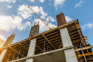 Obraz premium Extensive scaffolding providing platforms for work in progress on a new apartment block,Tall building under construction with scaffolds,Freestanding tower crane on a building site