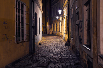 Fototapeta na wymiar view of a dark and illuminated cobblestone street in the old town of prague at night 2021