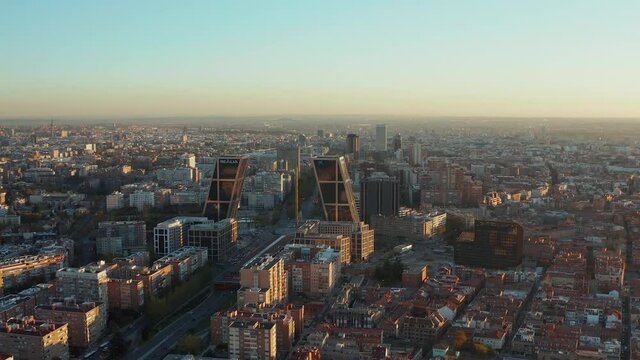 Slide and pan shot of Puerta de Europa modern business towers. Fly above city at sunset.