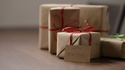 brown paper gift boxes with red bow on wood table with paper card