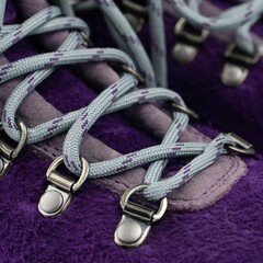 Fototapeta na wymiar Violet suede hiker boots with metal eyelets and lacing with blue laces close up