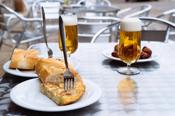 Ice cold beers pouring into glasses on table with spanish tapas