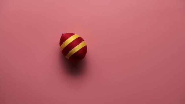 Rotation of colorful easter egg made from threads isolated on pink background. Easter concept.