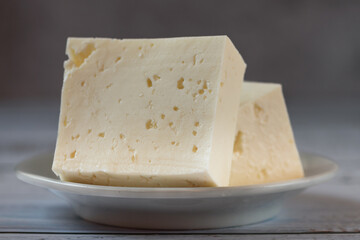 Large piece of feta cheese on dark wooden table. Selective focus