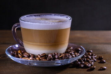 Cup of coffe with milk on a dark background. Hot latte or Cappuccino prepared with milk on a wooden table