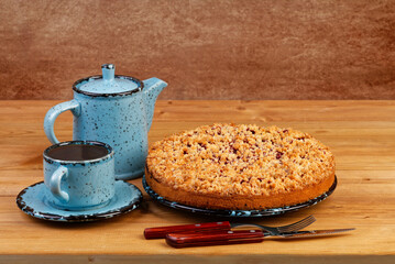 Homemade raspberries pie with streisel and cup of tea on wooden table. Copyspace.