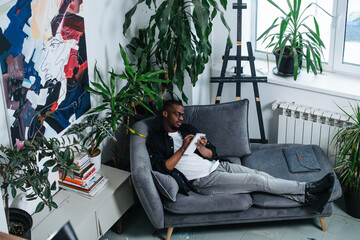African american man chilling on a sofa in the corner of his apartment.