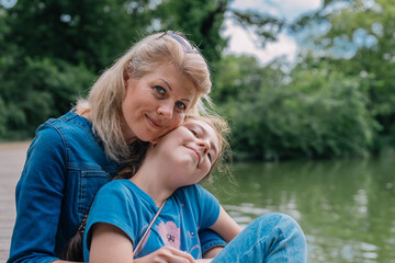 Portrait of a mother and daughter embracing, on the bank of a river.