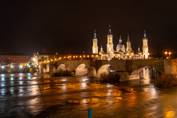 Panoramic at night on the Puente de Piedra next to the Basilica of Nuestra Señora del Pilar on the Ebro river in the city of Zaragoza, Aragon. Spain