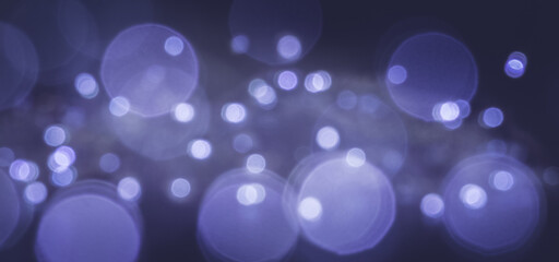 Blue and purple festive background with defocused lights of different diameters.