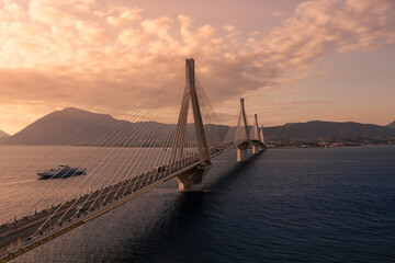 Huge suspension bridge with four large pillars over the sea strait at sunset, Peloponnese, Greece