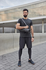 Full length shot of sportsman poses with fitness mat ready for workout looks determined into...