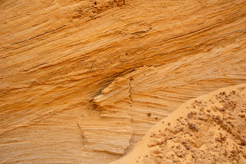 Textural sand, with  relief surface, multi-colored layers and different in size of granules, in outdoor sand career, after mining ore and sand for construction.