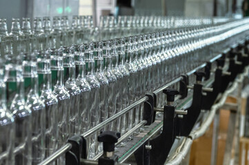 Fototapeta premium Conveyor with line of bottles for alcohol drinks in shop