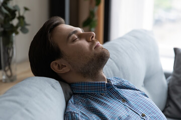 Close up handsome man falls asleep on sofa, put head on soft couch closed eyes breath fresh...