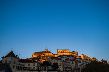 View of the old city of Coimbra in the sunset light against the background of the blue sky, Portugal.