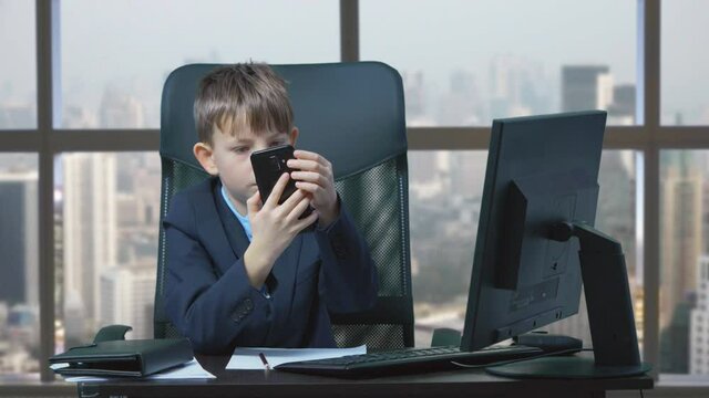 Little child with suit and tie  typing and talk on phone, window city view