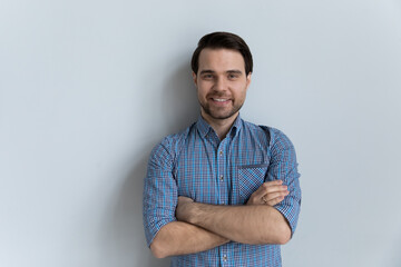 Attractive millennial guy wear casual blue shirt posing on gray wall studio background, single man...