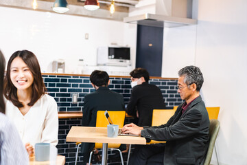 明るい雰囲気の社員食堂でランチを取るオフィスワーカー