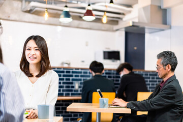 明るい雰囲気の社員食堂でランチを取るオフィスワーカー