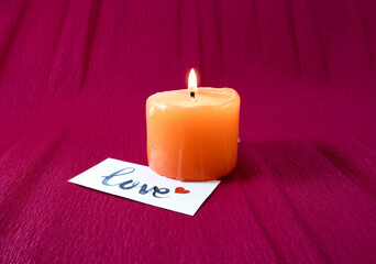 Candle with love card on red background