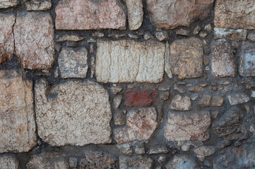 Detail of a wall built from a multi-colored patchwork of stones.  