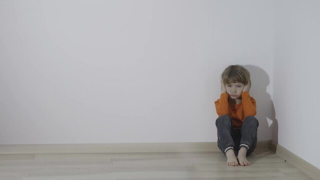 Hand silhouettes reflect on wall arguing child sit in corner, hands cover ears, conceptual