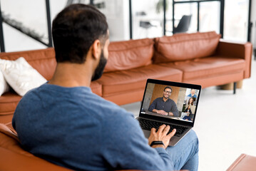 Male employee involved video meeting on the laptop with diverse workteam, indian man using computer app for video connect with diverse colleagues, brainstorming online, discussion during video meeting