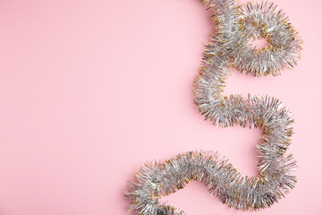 Sparkling tinsel on pink background, top view. Space for text