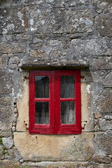 Window on Stone Wall with Rustic Red Wooden Frame. Facade of old and uninhabited style house.