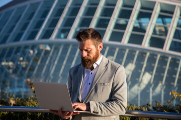 businessman with laptop in an urban setting modern buildings in background