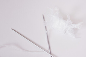 Recycled plastic yarn concept, knitting needles, tangle of sliced plastic package on gray background