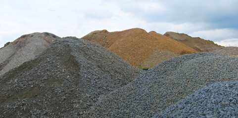 Piles of gravel and yellow sand used for the construction forming shapes of mountains