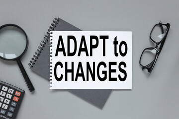 ADAPT TO CHANGE, blank notebook on gray background near magnifier of glasses calculator