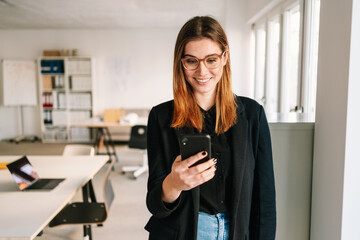 Young businsswoman smiling as she reads a phone message