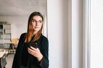 Pensive thoughtful office worker standing staring out of window